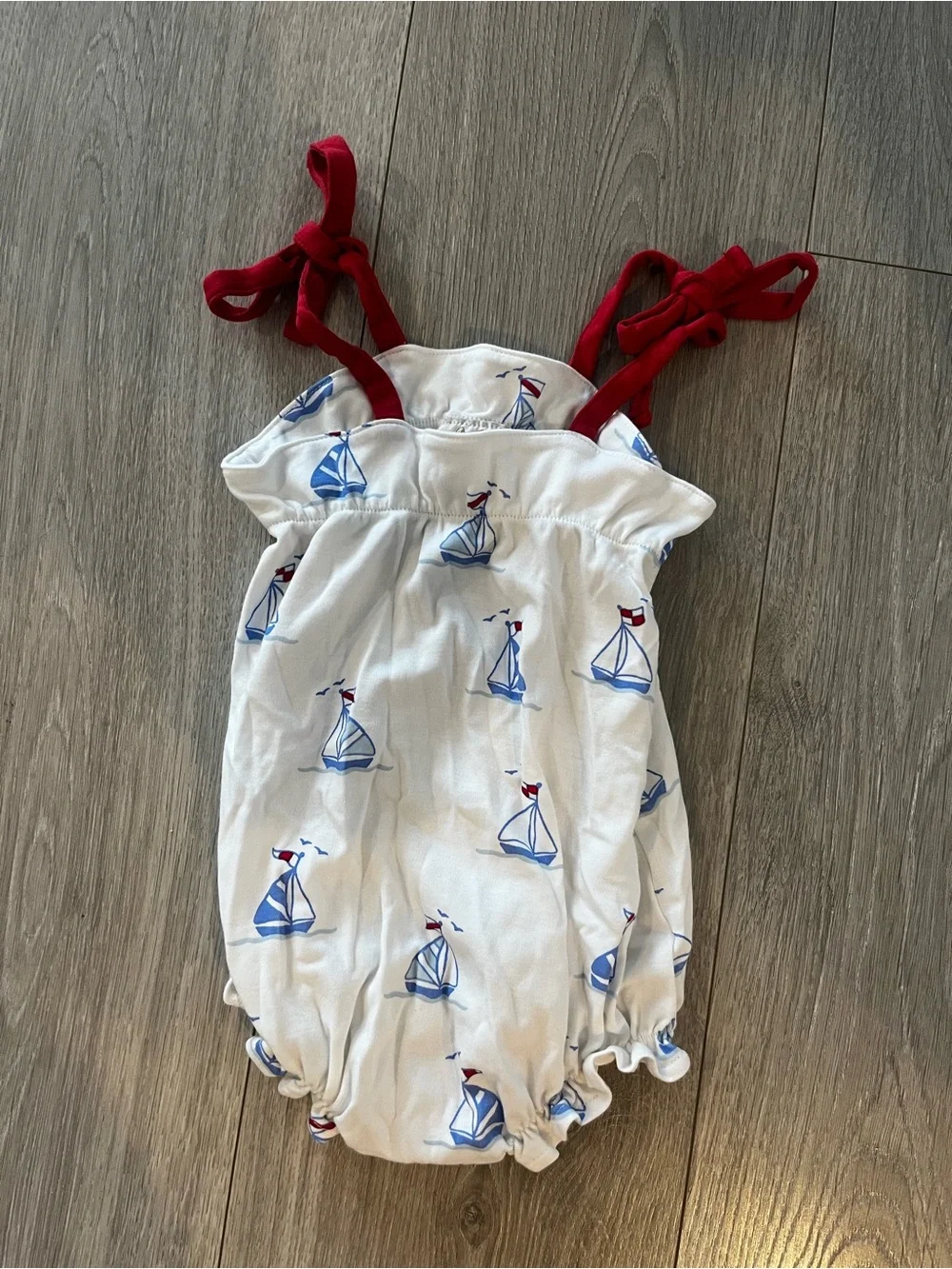 The Beaufort Bonnet Company White Romper with Blue Sailboats and Red Tie Straps